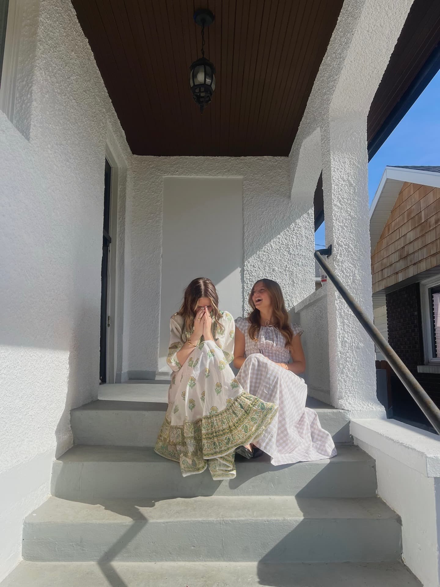 Two women laughing on a white porch